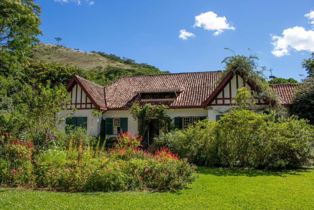 uma casa com um jardim com flores no quintal em Pousada da Alcobaça em Itaipava