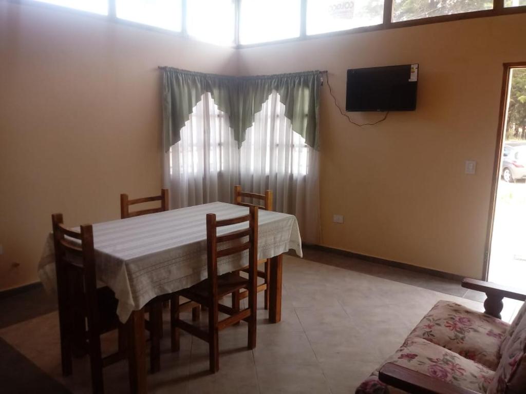 a dining room with a table and chairs and a television at Las casitas de Mar in Mar de Ajó