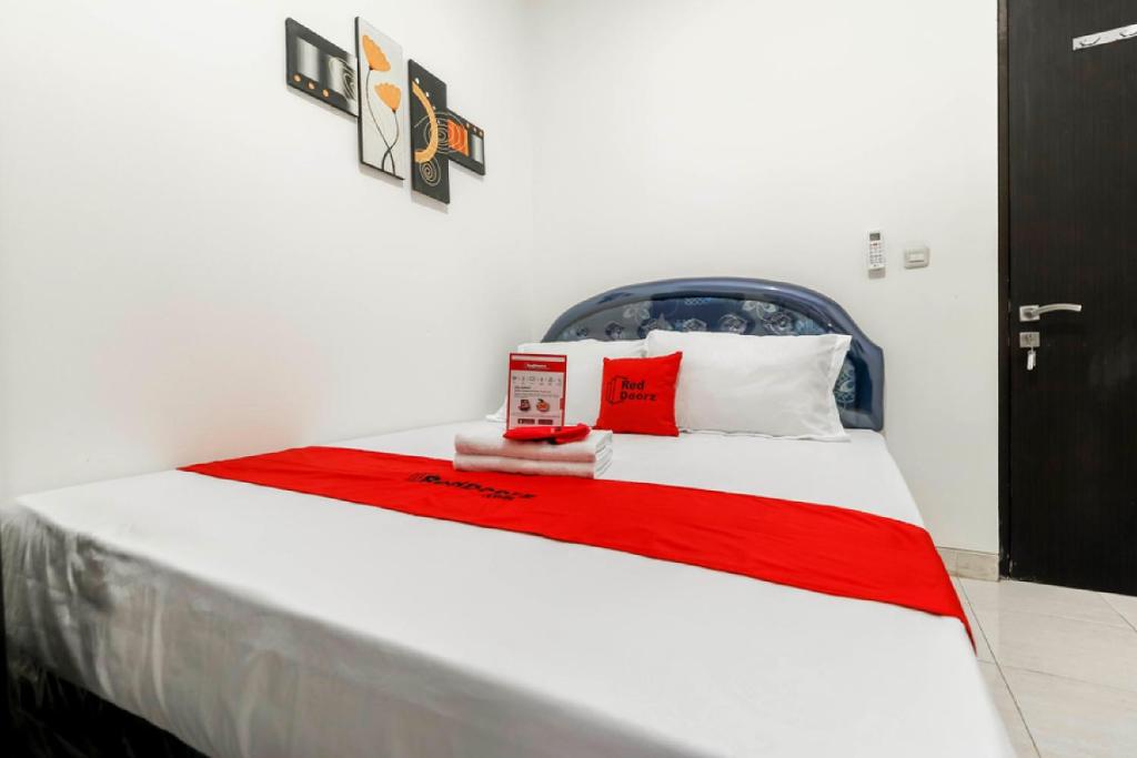 a bedroom with a bed with a red blanket at RedDoorz Plus near Trisakti University in Jakarta