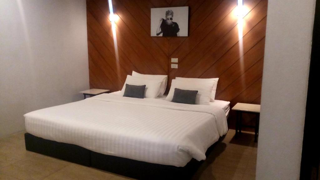 a bedroom with a large white bed with a wooden wall at The Rodman Hotel in Chiang Mai