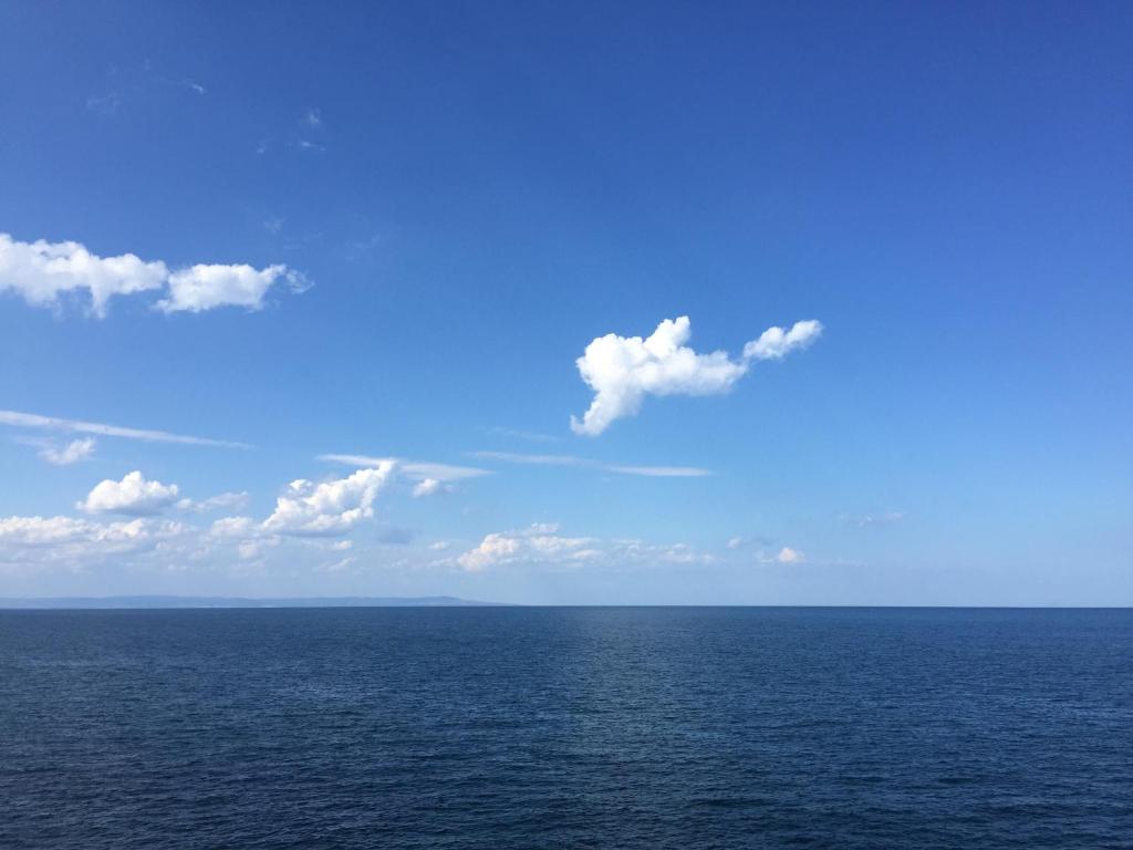 een grote hoeveelheid water met een blauwe lucht en wolken bij Deep Blue Guest House in Sozopol