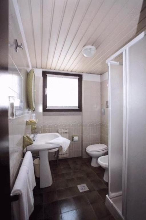 łazienka z umywalką, toaletą i oknem w obiekcie Hotel Derby w Sirmione