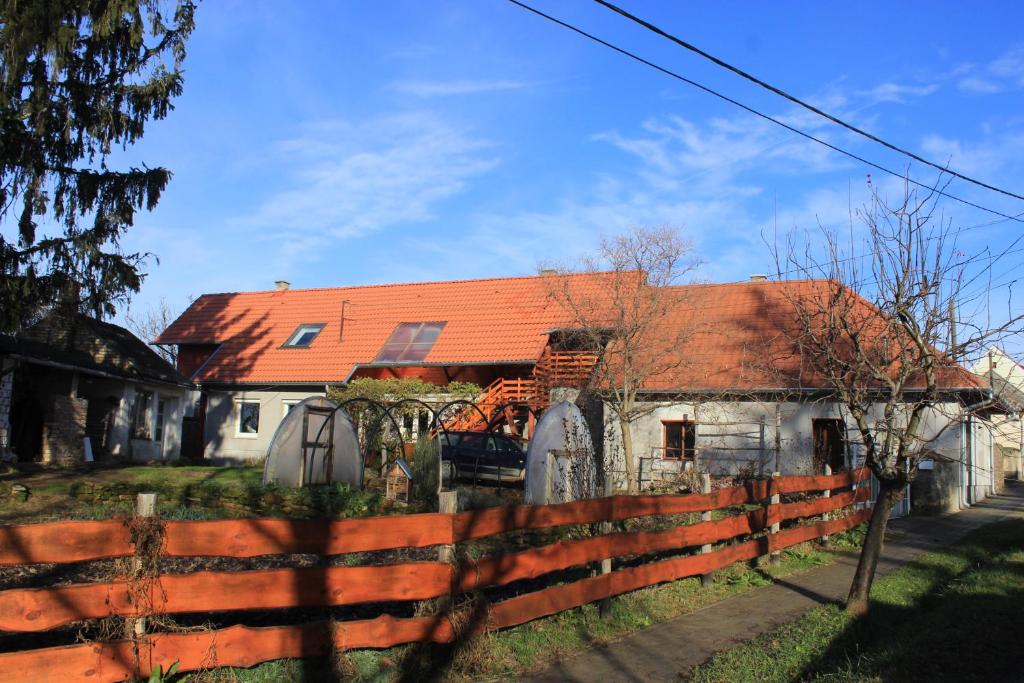 a house with an orange roof behind a fence at A Kert Apartman in Rezi