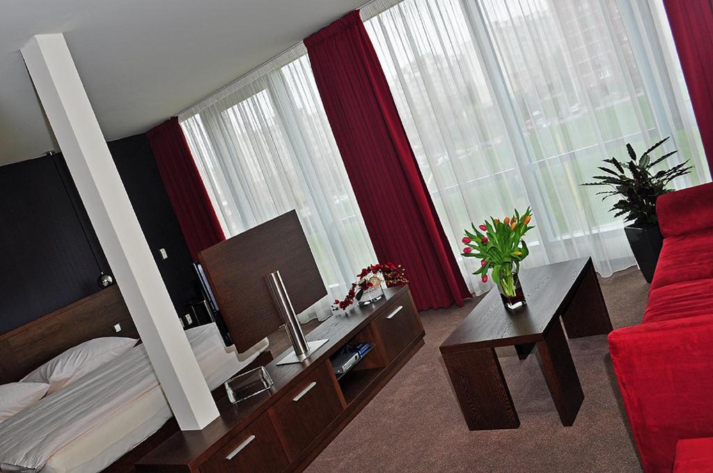 a hotel room with a bed and a red couch at Glass House Kosice in Košice