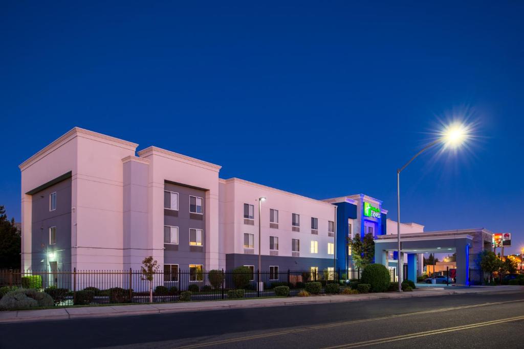 un edificio rosa en una calle de la ciudad por la noche en Holiday Inn Express Stockton Southeast, an IHG Hotel, en Stockton