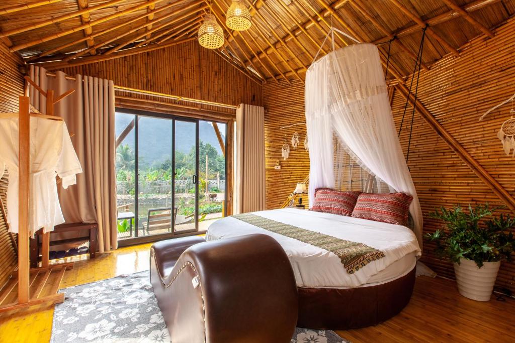 a bedroom with a canopy bed and a window at Trang An Lamia Bungalow in Ninh Binh
