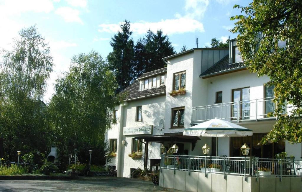 ein weißes Gebäude mit einem Schirm davor in der Unterkunft Waldpension zum Felsenkeller in Lichtenfels-Sachsenberg