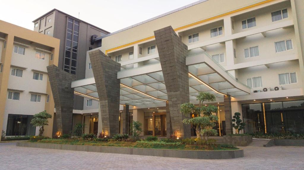 Pollos Hotel & Gallery في Rembang: مبنى ابيض كبير امامه اشجار