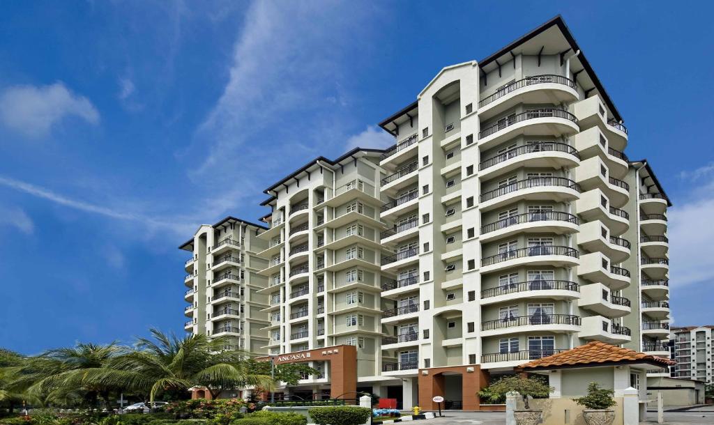 a tall white apartment building with palm trees at Ancasa Residences, Port Dickson by Ancasa Hotels & Resorts in Port Dickson