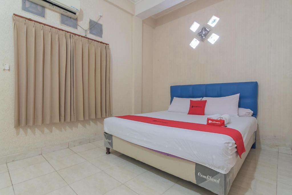 a bedroom with a large bed with a blue headboard at RedDoorz Syariah near Terminal Batu Ampar 2 in Balikpapan