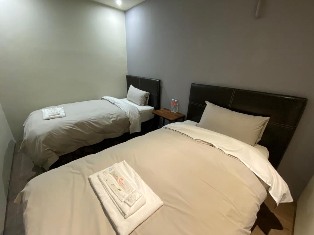 a hotel room with two beds with white sheets at Saint Hostel in Beigang