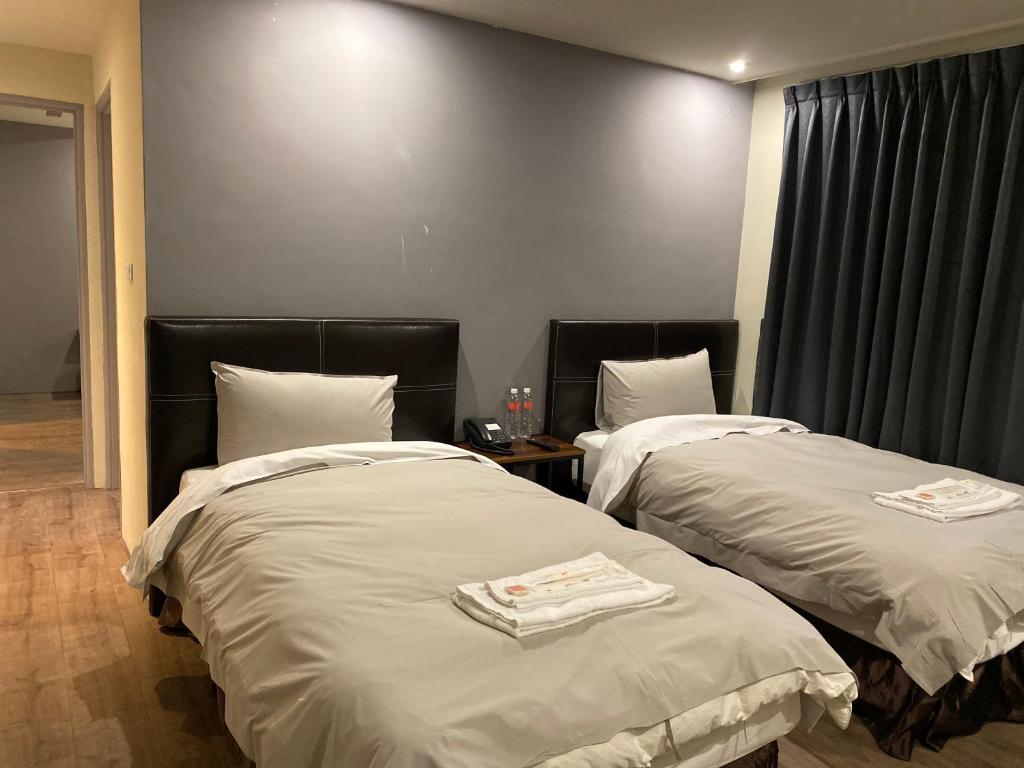 two beds in a hotel room with towels on them at Saint Hostel in Beigang