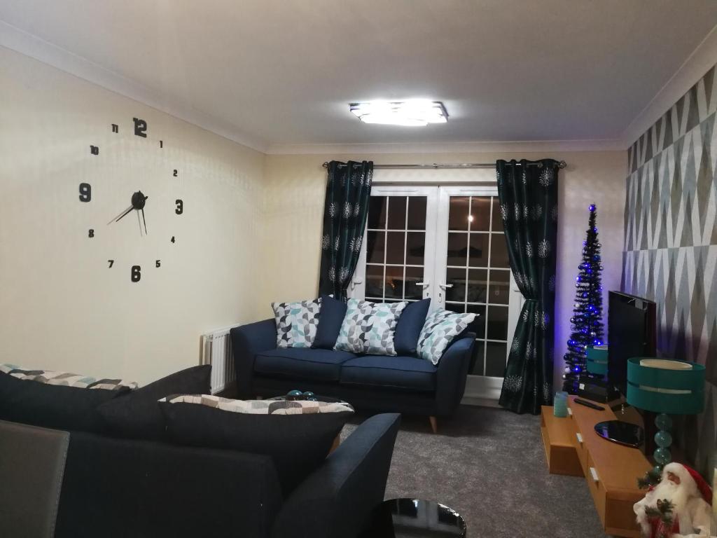 a living room with a blue couch and a christmas tree at Stewartfield Gardens Apartment in East Kilbride