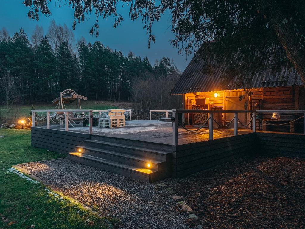 Cabaña de madera con terraza por la noche en Markuse puhkemaja, en Palamuste