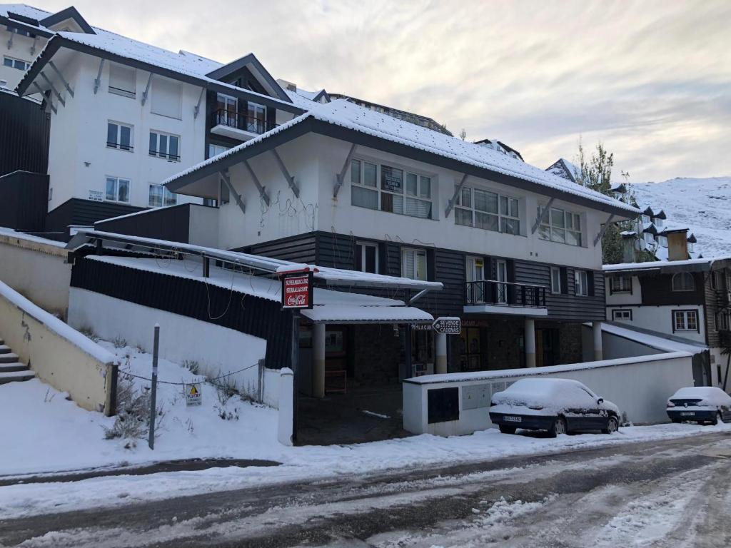 una casa cubierta de nieve con un coche aparcado delante de ella en GLP Sierra nevada, en Sierra Nevada