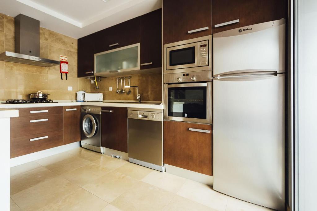 a kitchen with stainless steel appliances and wooden cabinets at Baia Residence 2 - Holiday Apartments - By SCH in São Martinho do Porto