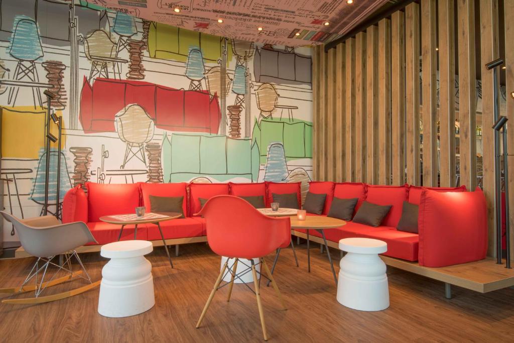 a restaurant with a red couch and tables and chairs at ibis Alger Aéroport in Alger
