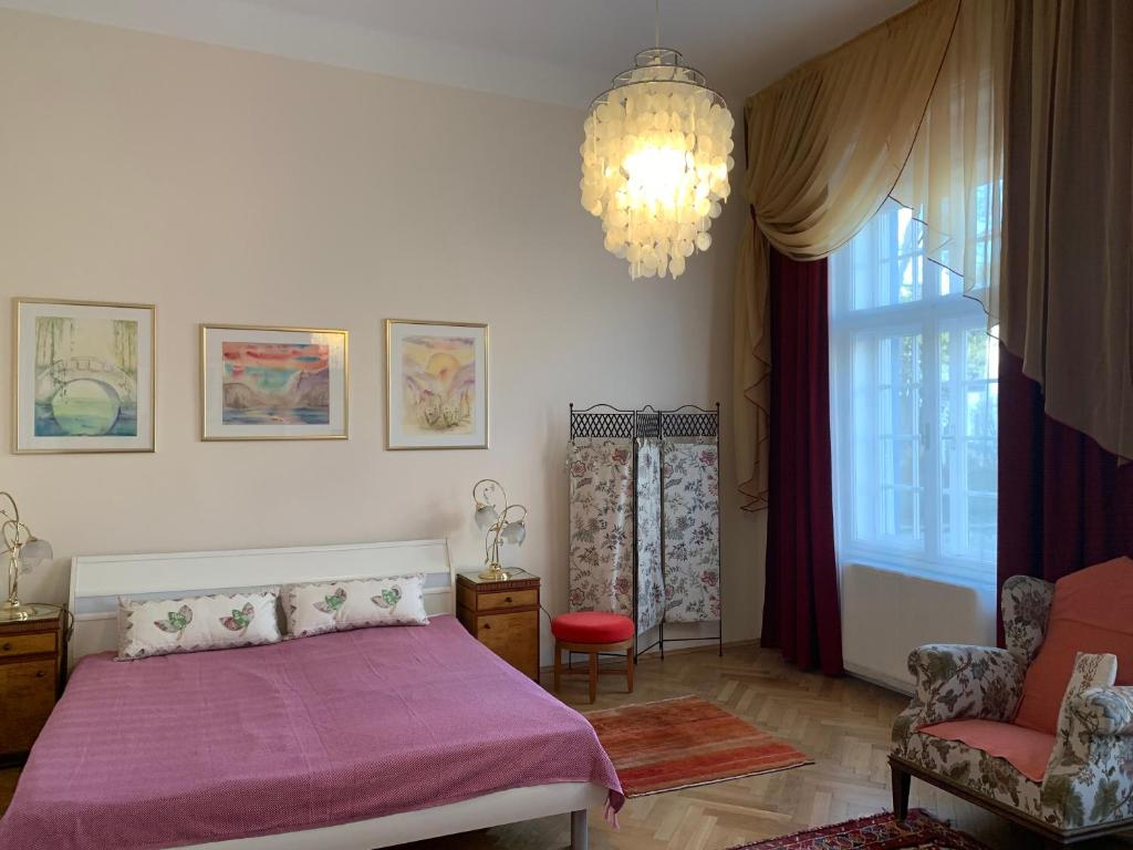 a bedroom with a pink bed and a chandelier at Villa Pazelt Top2 in Bad Vöslau