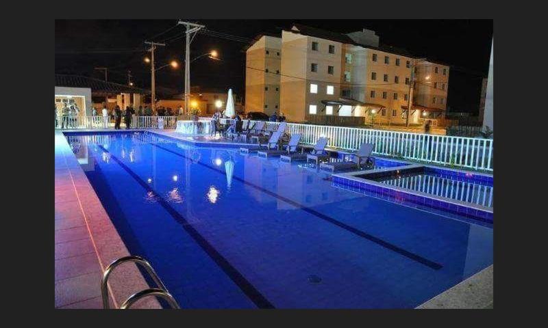 una grande piscina notturna con illuminazione blu di Apartamento na Praia a Ilhéus