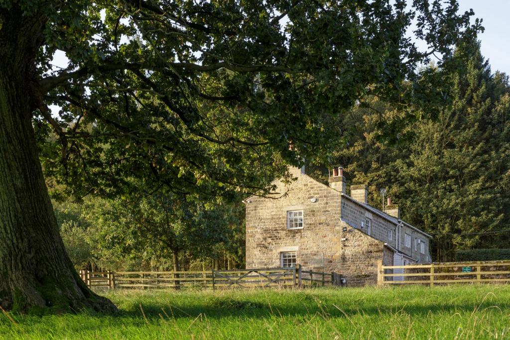 an old stone building in a field with a tree at Carr House in Leeds