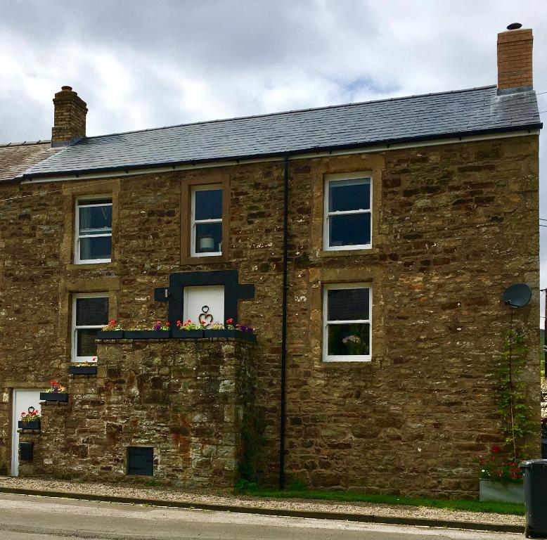 a brick building with a window with flowers on it at Fell View, Slaggyford in Brampton