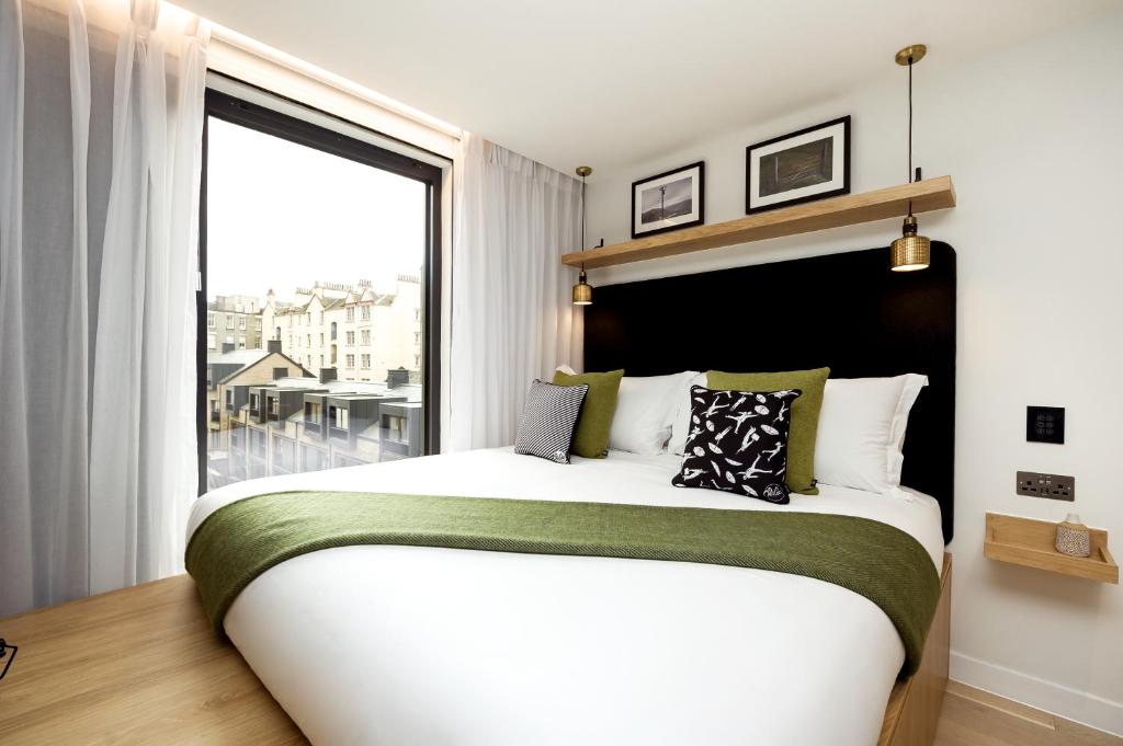 Wilde Aparthotels Edinburgh Grassmarket في إدنبرة: غرفة نوم بسرير كبير مع نافذة كبيرة