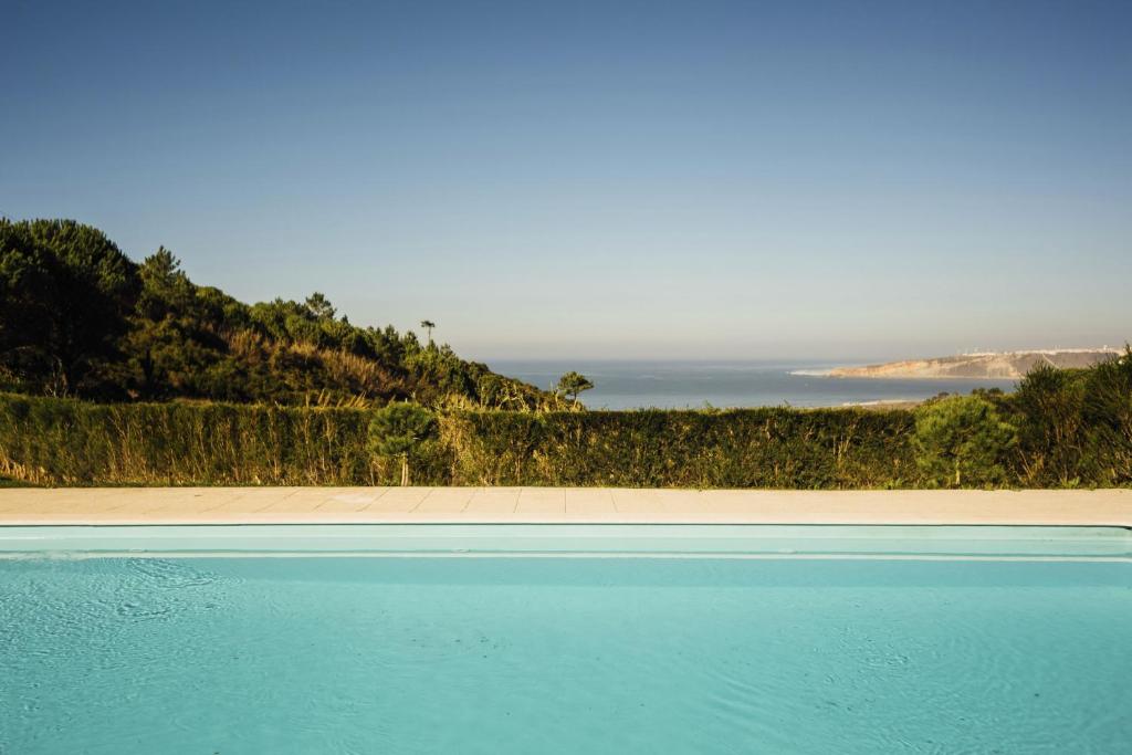 a blue swimming pool with a view of the ocean at TradeWinds - Holiday Houses - By SCH in São Martinho do Porto