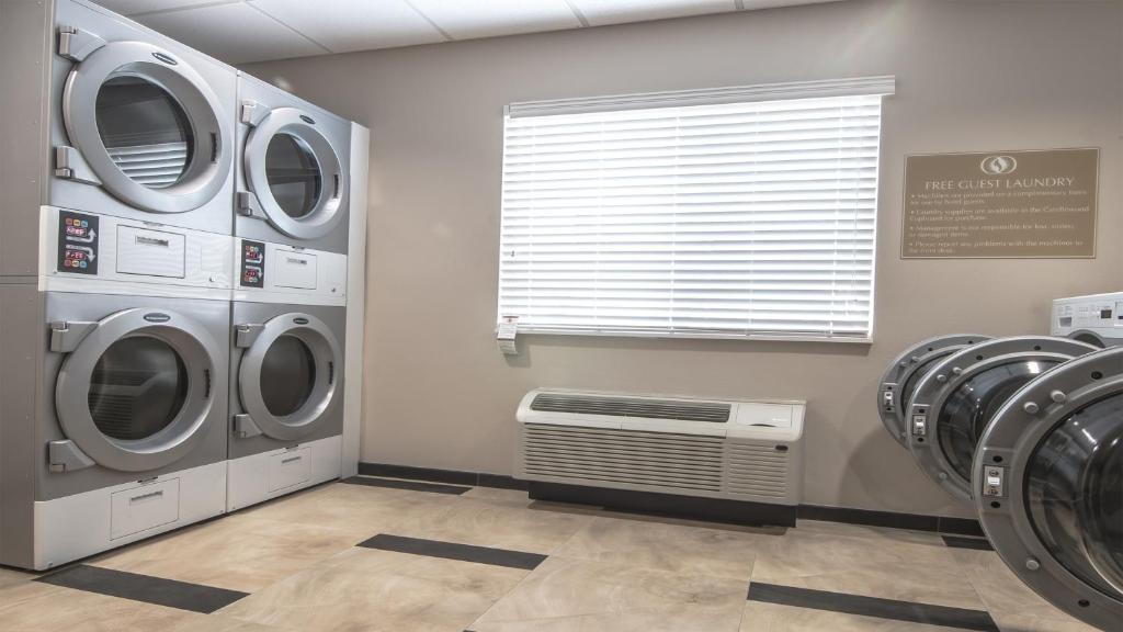 a laundry room with three washing machines and a window at Candlewood Suites Gonzales - Baton Rouge Area, an IHG Hotel in Gonzales