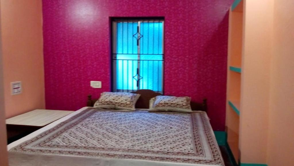 een bed in een kamer met roze muren en een raam bij Vamoose Mangrove Pitta in Kendrāparha