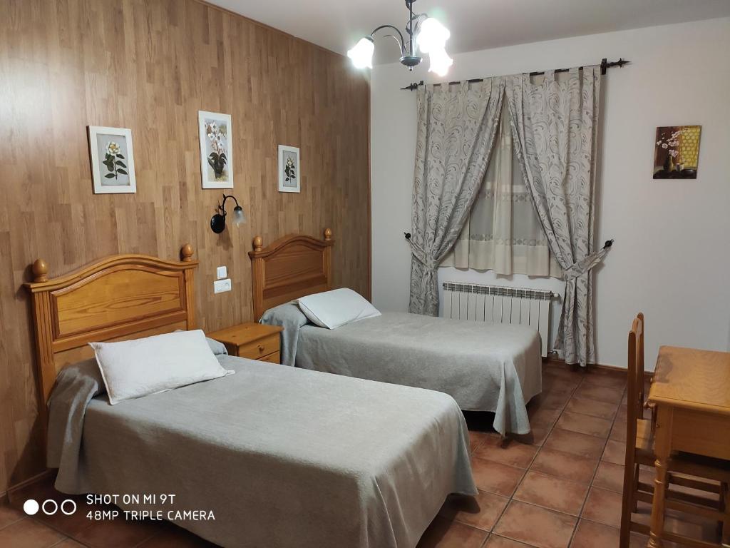 ビジャヌエバ・デ・ロス・インファンテスにあるCasa Rural IRISのベッド2台と窓が備わるホテルルームです。