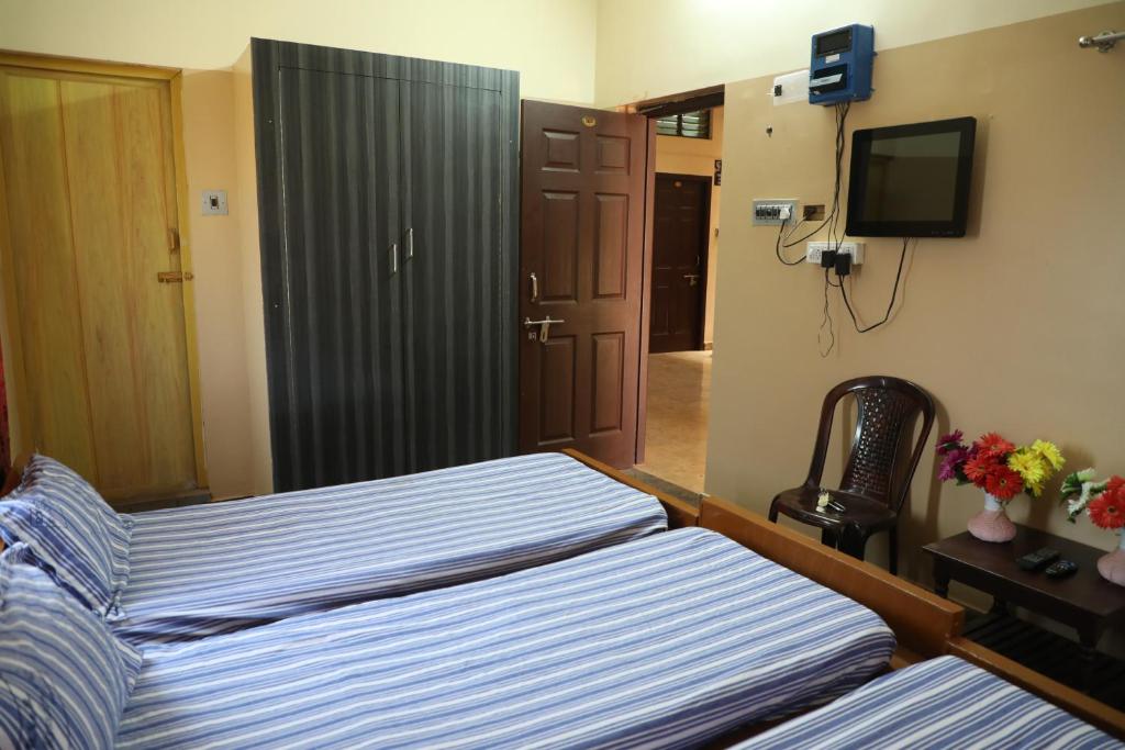 ein Schlafzimmer mit 2 Betten und einem TV in der Unterkunft R. VE. R Residency in Thanjavur