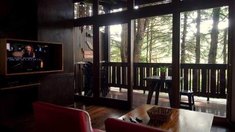 un salon avec une table et un balcon avec une télévision dans l'établissement Posta Chimango, Cabañas frente al Golf Los Acantilados, à Mar del Plata