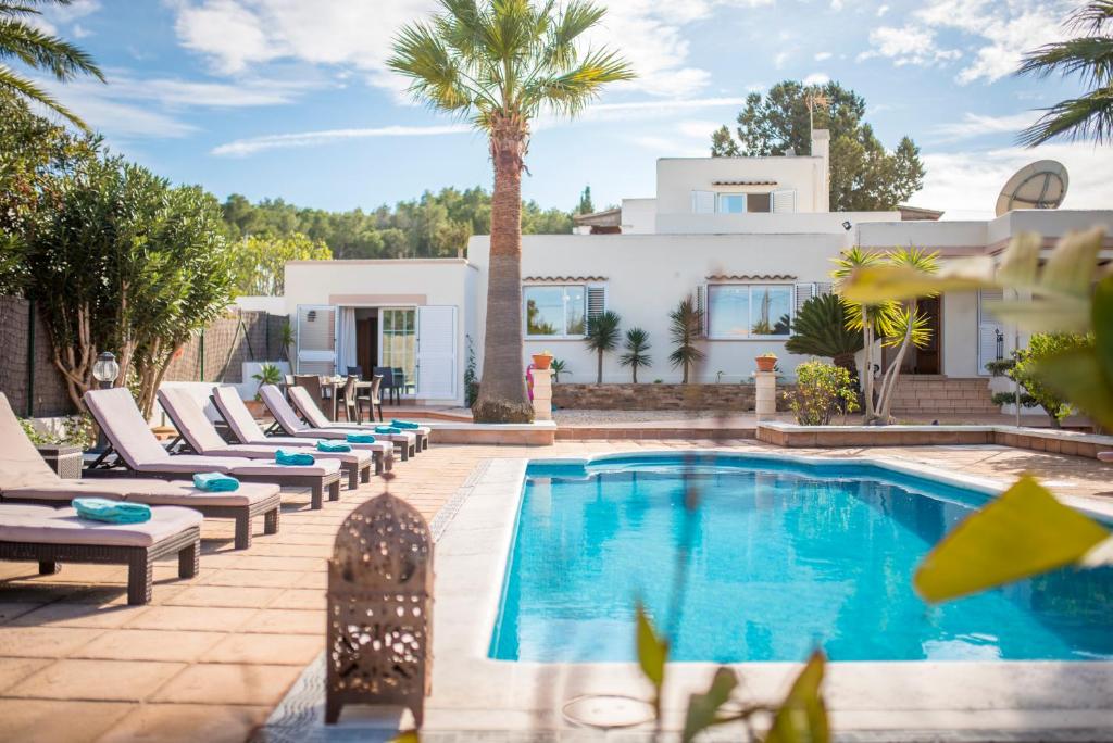 uma piscina com espreguiçadeiras e uma casa em Villa Can Petrus, con piscina y wifi gratis em San Antonio Bay