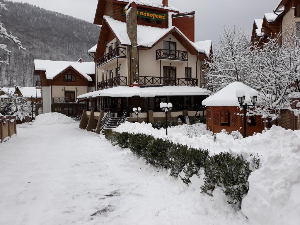 un grand bâtiment avec de la neige au sol dans l'établissement Tsvit Paporoti, à Yaremtche