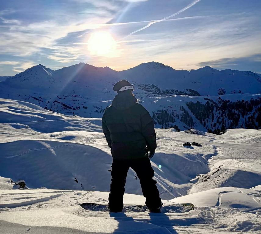 un hombre de pie en una tabla de snowboard en la cima de una montaña en CERRO TORRE PLAGNE, en Aime La Plagne