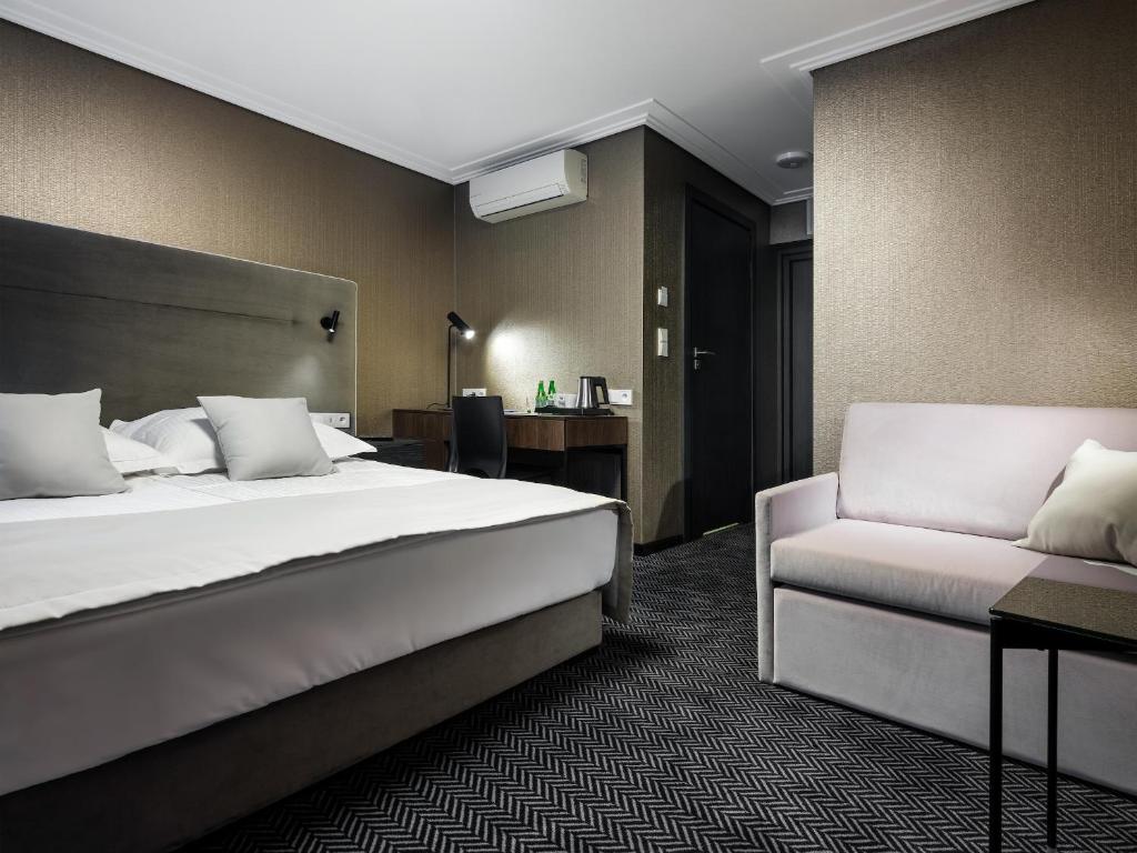 a hotel room with a bed and a couch at Hotel Logos Kraków in Krakow