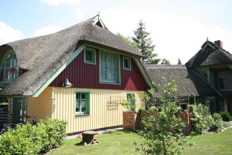 a red and yellow house with a thatched roof at "Kajüte 1" by Ferienhaus Strandgut in Born