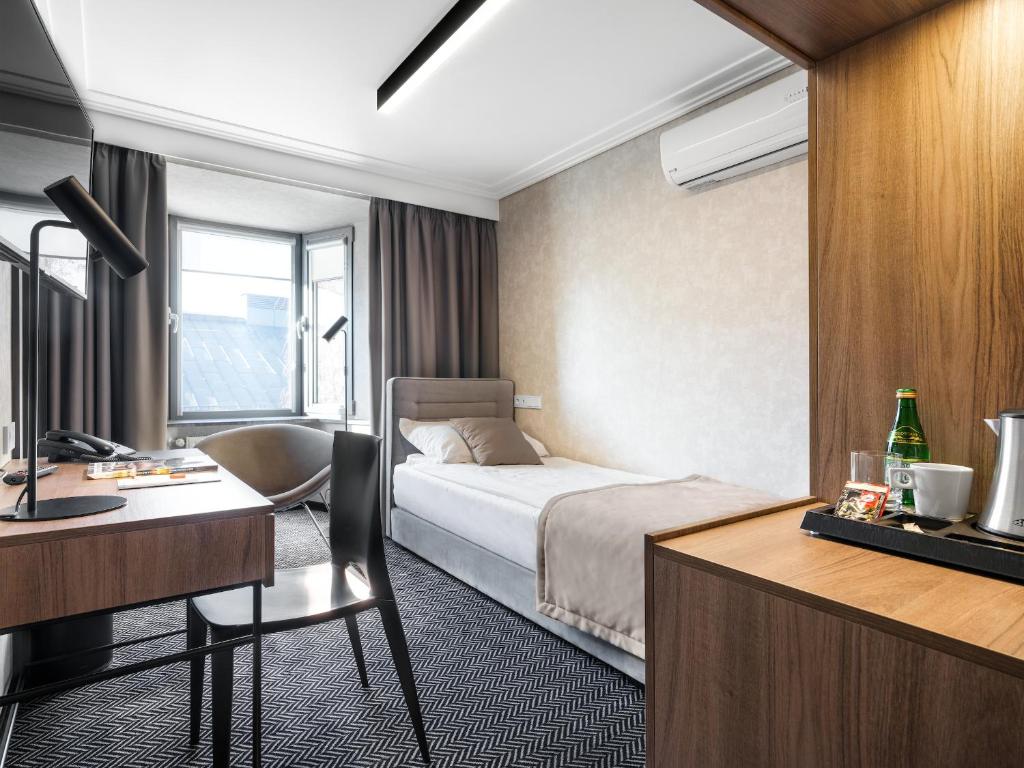 a hotel room with a bed and a desk at Hotel Logos Kraków in Krakow