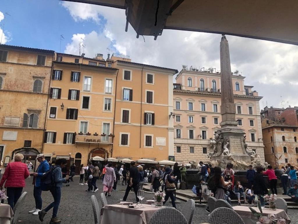 uma multidão de pessoas andando em torno de uma cidade com edifícios em The Pantheon Eyes em Roma