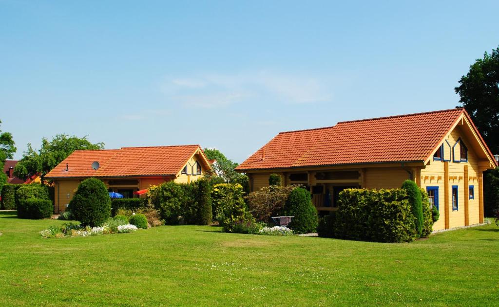 uma casa com um telhado vermelho num relvado verde em Ferienanlage Doll em Neuendorf A