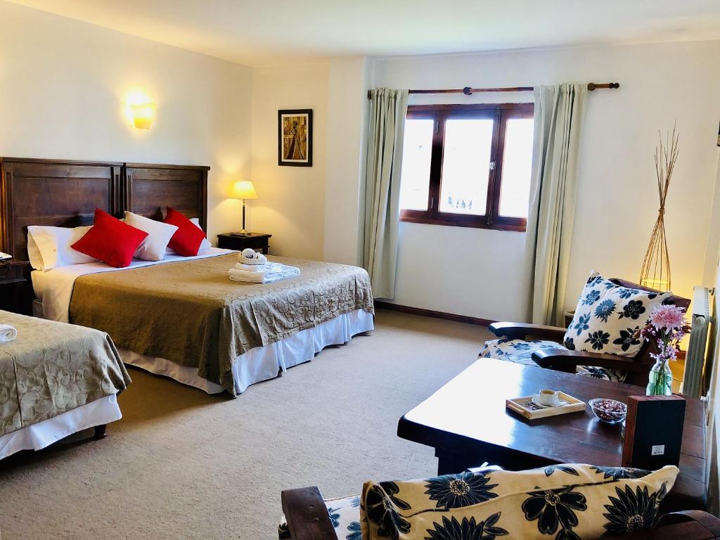 um quarto de hotel com duas camas e um sofá em Kalken Hotel by MH em El Calafate