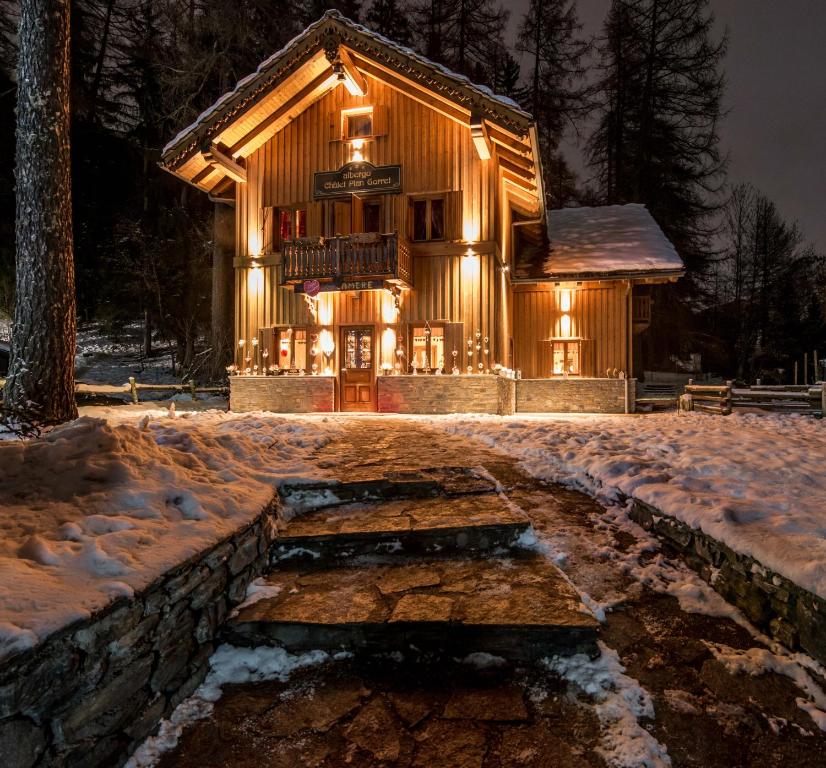 a log cabin with lights on it in the snow at Chalet Plan Gorret in Courmayeur