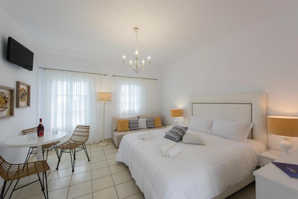 1 dormitorio con 1 cama blanca grande, mesa y sillas en Eutuxia Rooms & Studios en Apollonia