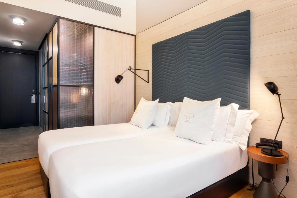 a bedroom with a large white bed and a lamp at One Shot Tabakalera House in Donostia-San Sebastián