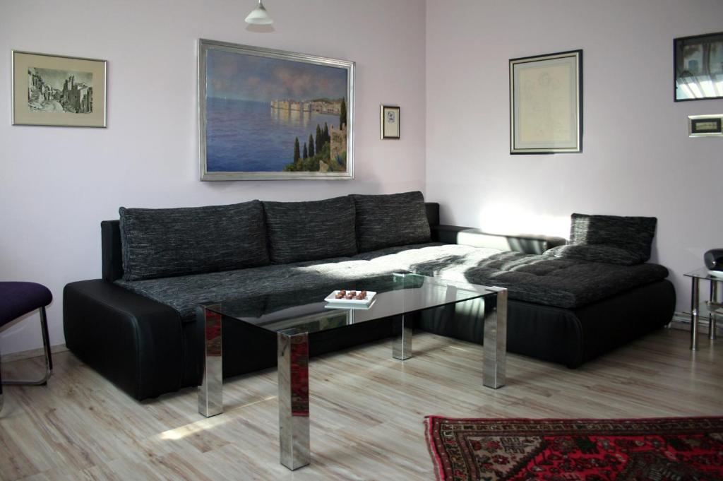 a living room with a black couch and a glass table at Apartments ABA Zagreb in Zagreb