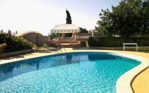 a large blue swimming pool in front of a house at Lageado Park in Albufeira