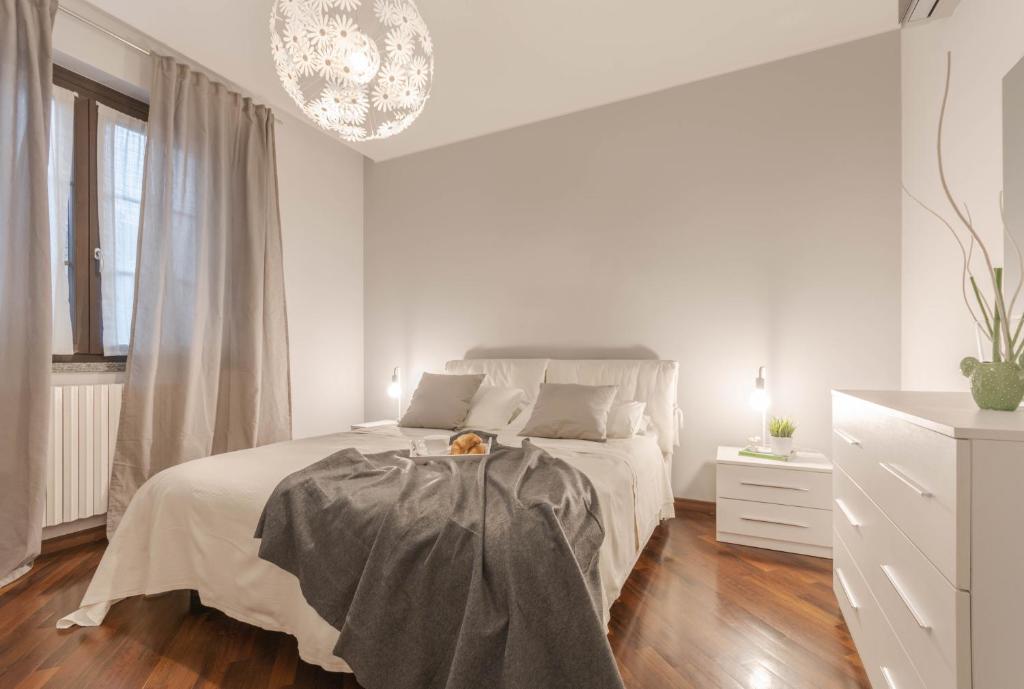 a white bedroom with a bed and a chandelier at Welcome to Milan and More! in Varedo
