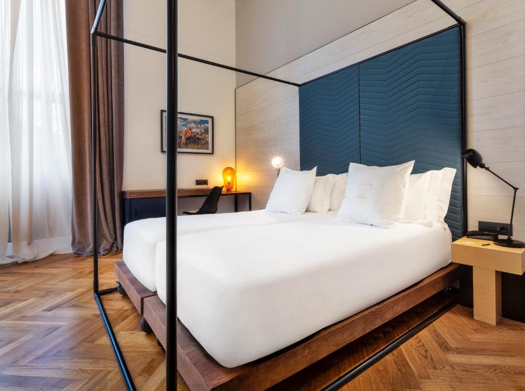 a bedroom with a large white bed with a blue headboard at One Shot Tabakalera House in Donostia-San Sebastián