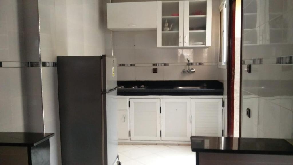 eine Küche mit weißen Schränken und einem schwarzen Kühlschrank in der Unterkunft MARIA HOUSE in Imsouane