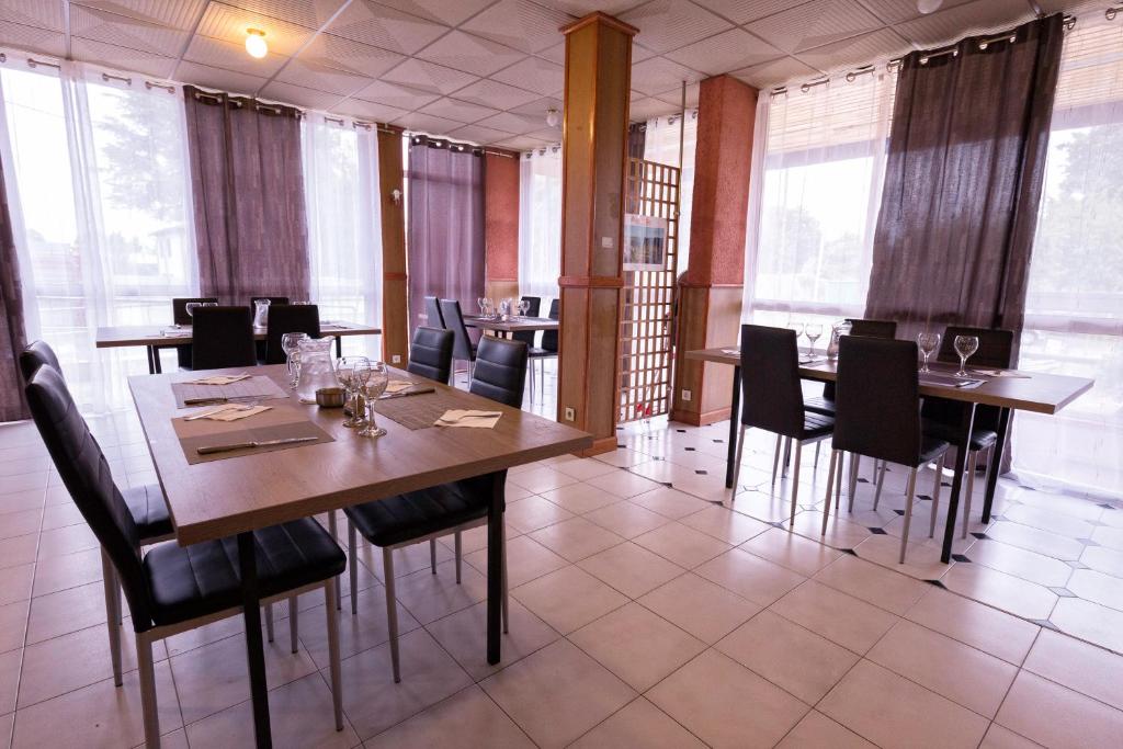a dining room with wooden tables and black chairs at Dortoirs Rocade 2 in Pamiers
